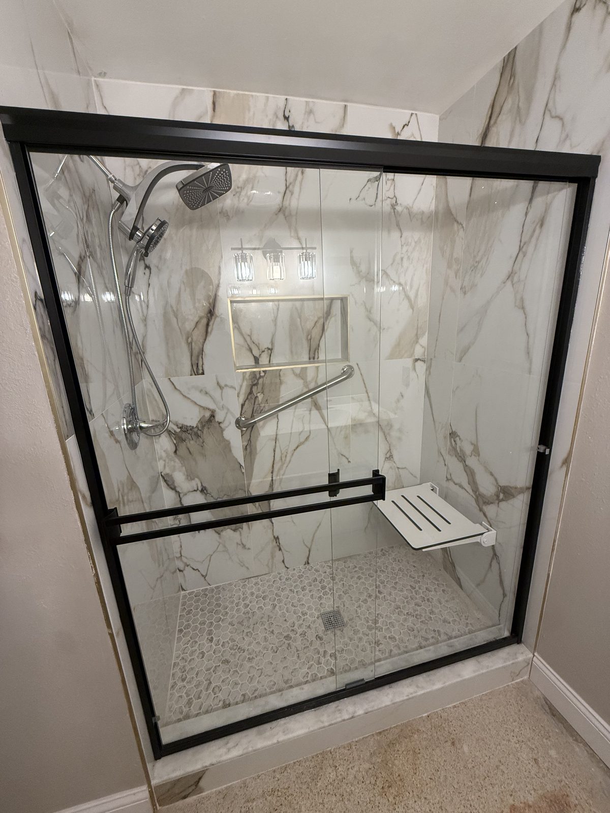 Walk-in marble shower with black-framed glass enclosure