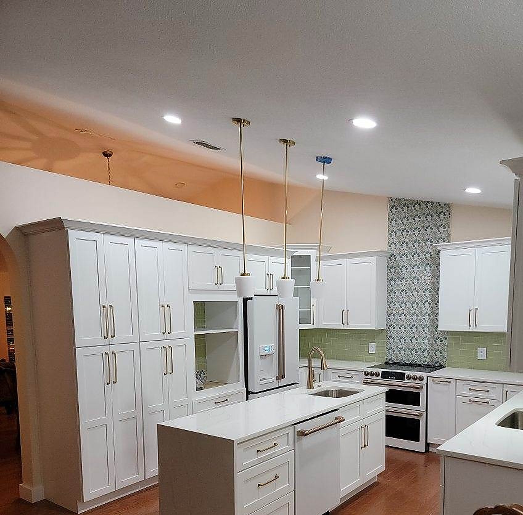 White shaker kitchen with quartz island and brass pendants